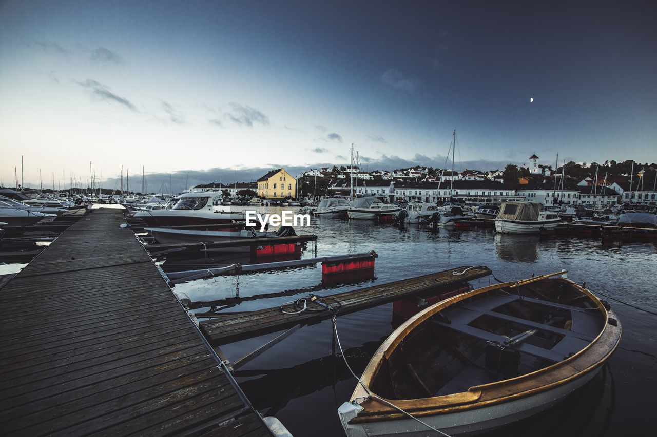 Sailboats moored at harbor against sky