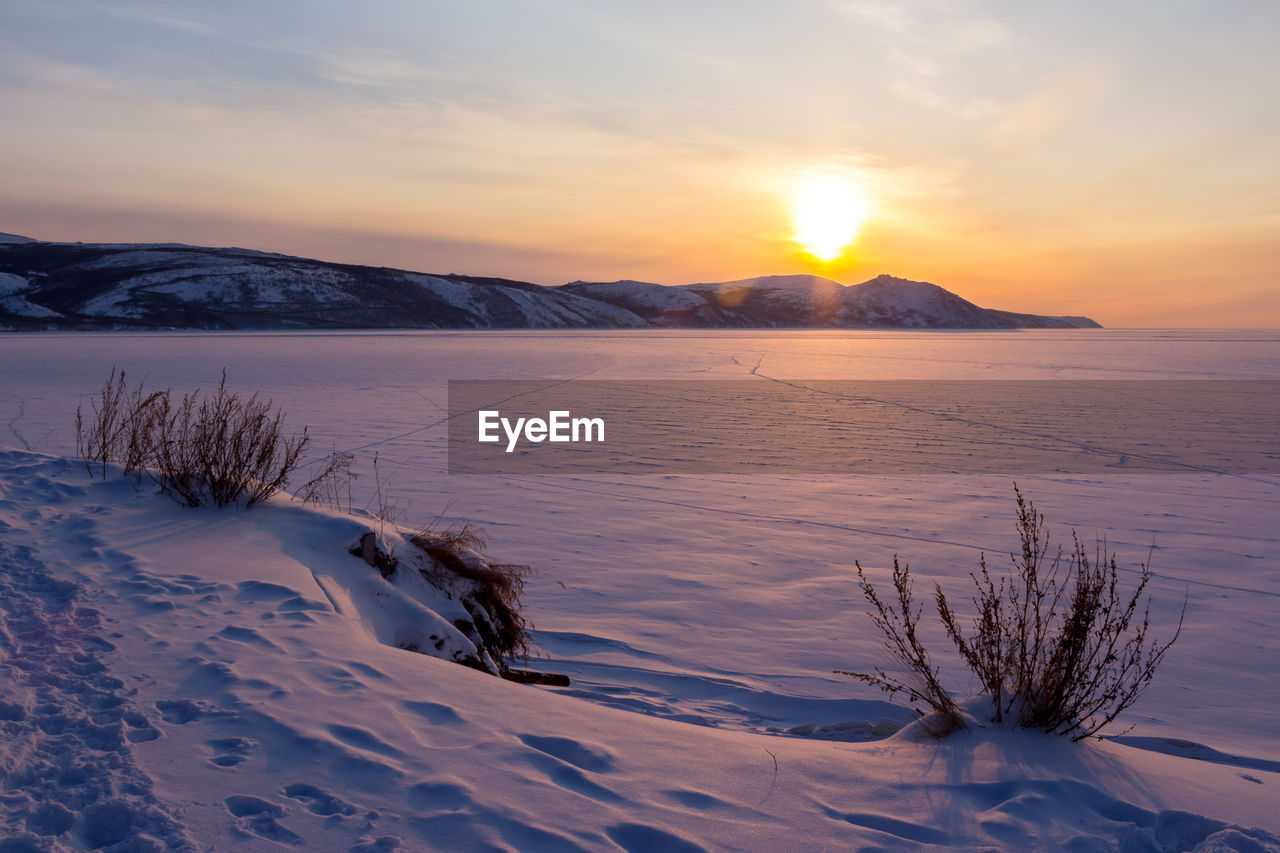 Scenic view of snow covered mountains against sky during sunset