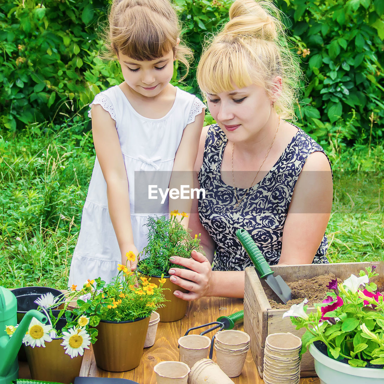 portrait of smiling young woman gardening while sitting outdoors