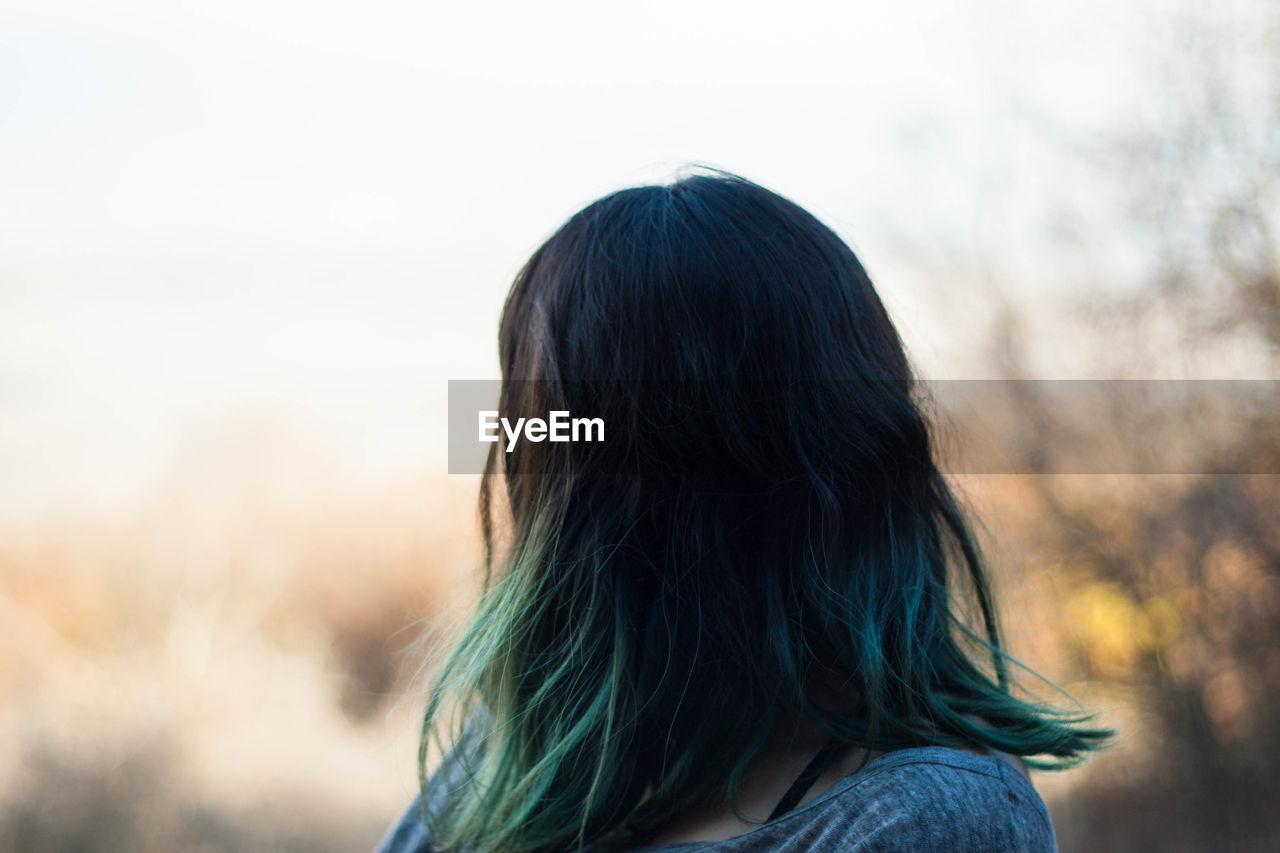 Woman with dyed hair against sky during sunset