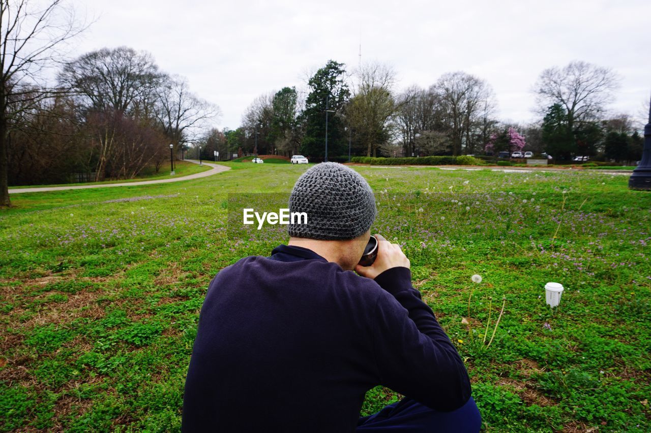 MAN PHOTOGRAPHING ON GRASSY FIELD