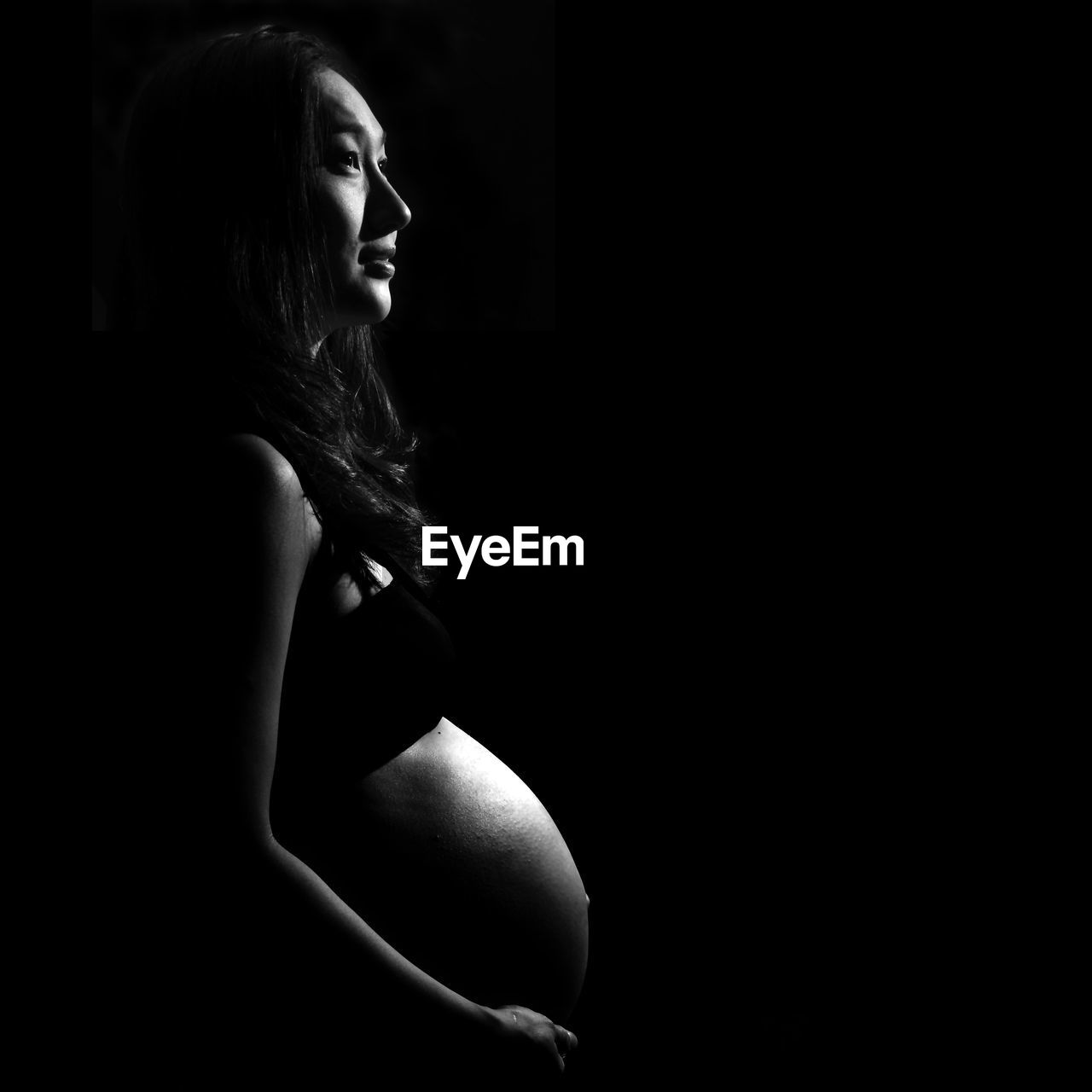 Pregnant woman standing against black background