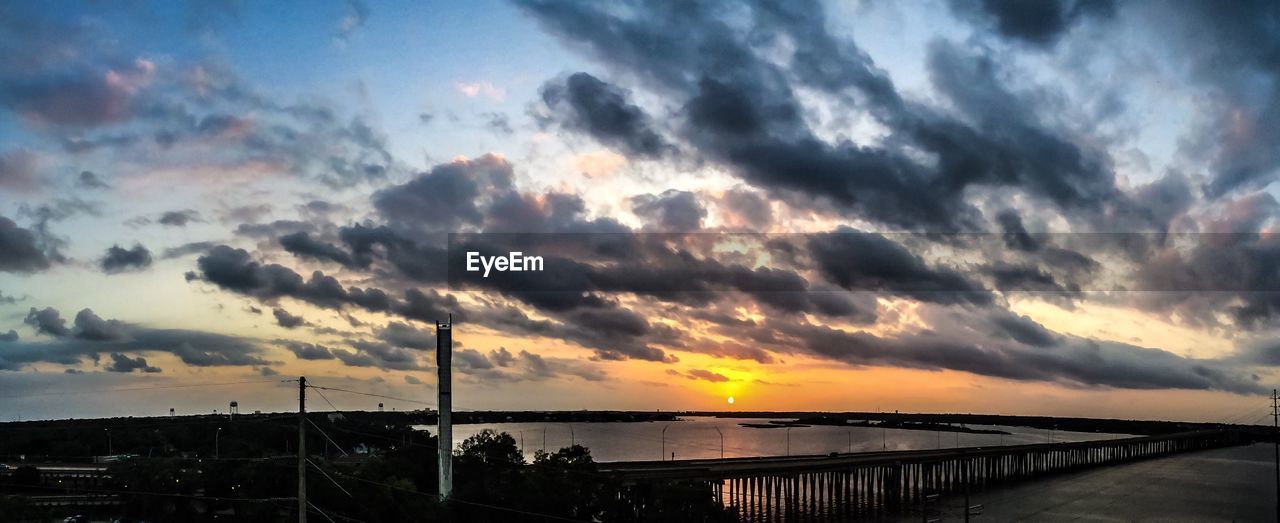 Scenic view of sea against cloudy sky during sunset