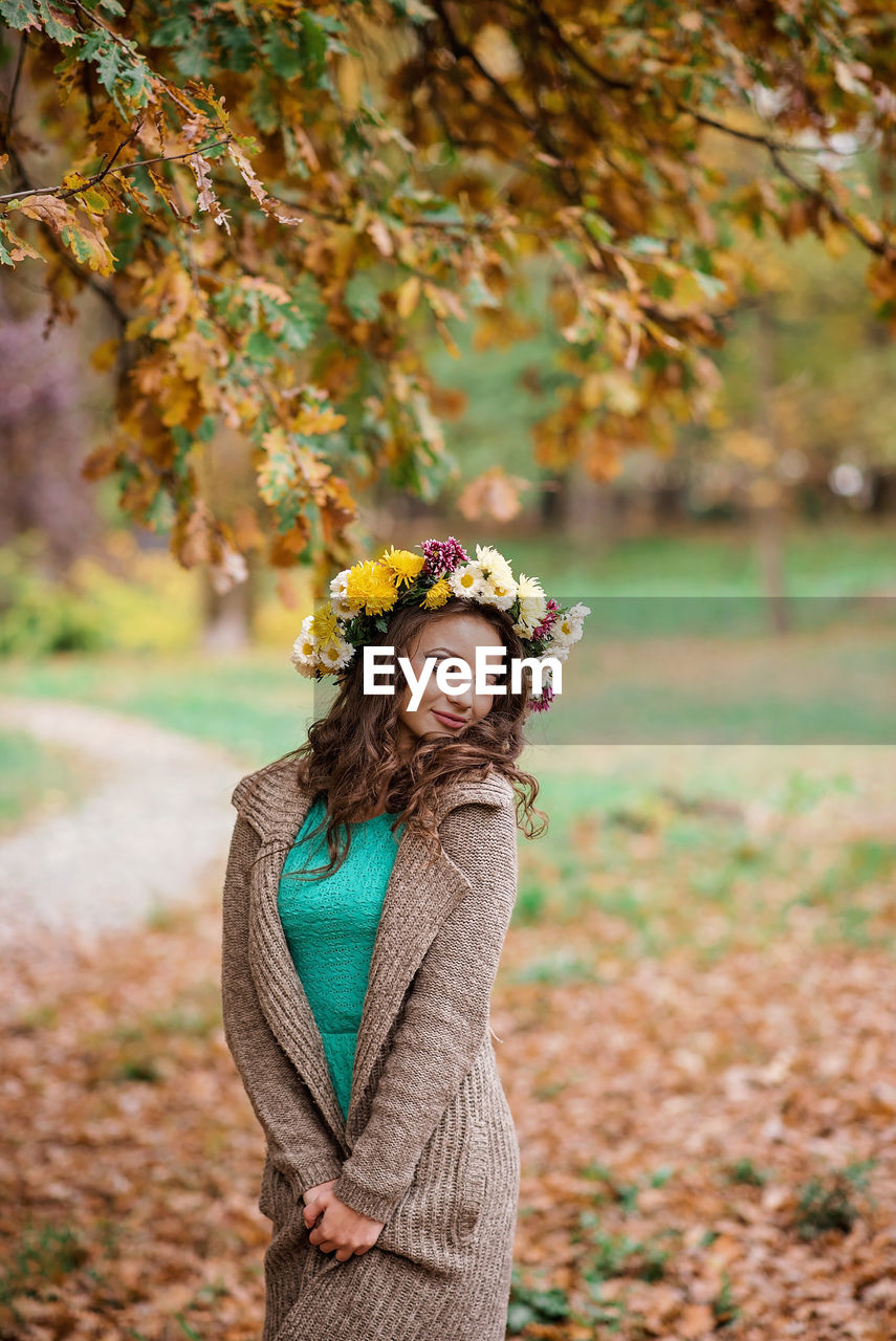 Portrait of woman standing by tree during autumn