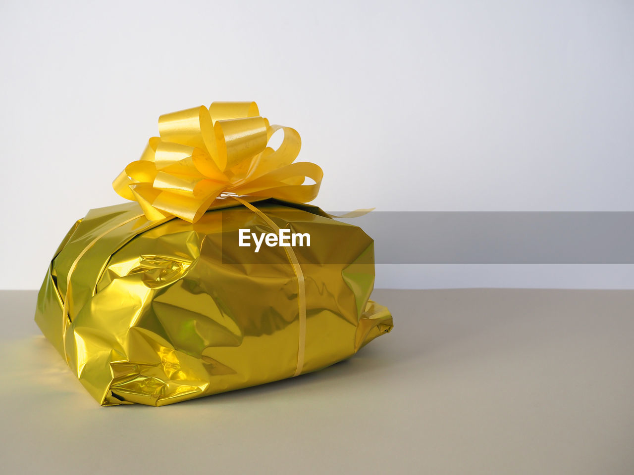 yellow, gift, gold, paper, present, ribbon, copy space, wrapping paper, studio shot, indoors, surprise, wrapped, celebration, no people, bow, box, tied bow, holiday, gift box, container, single object, emotion, art, christmas, wedding favors, shiny, wealth, still life