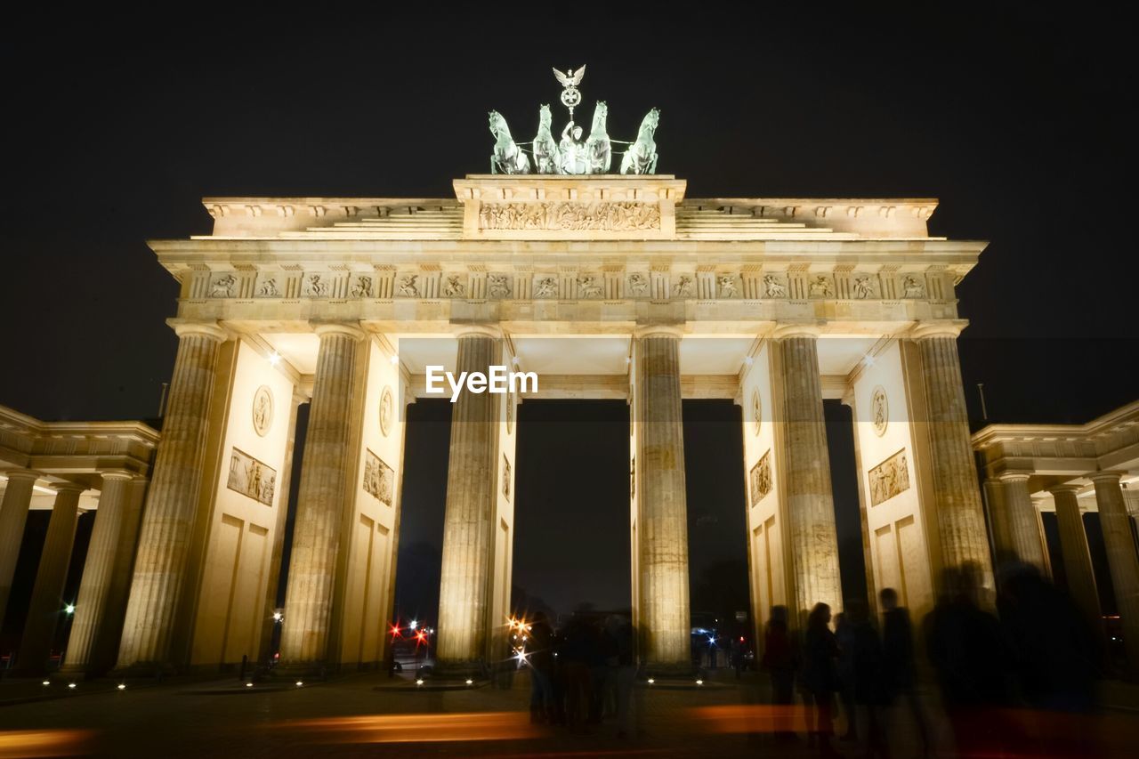 Silhouette people against illuminated brandenburg gate at night