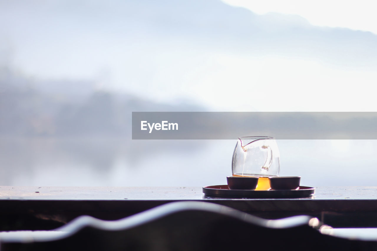 Morning cup of hot tea with lake background at sunrise.