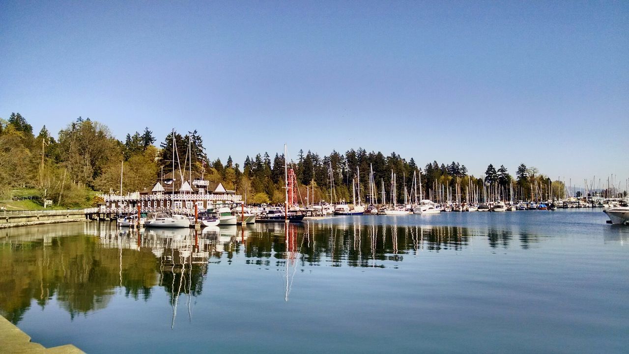 Sailboats moored in lake against clear sky