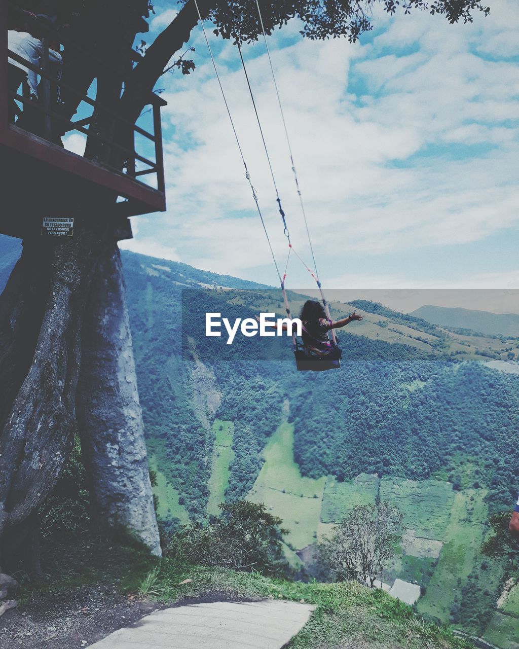 LOW ANGLE VIEW OF MAN HANGING ON TREE AGAINST SKY