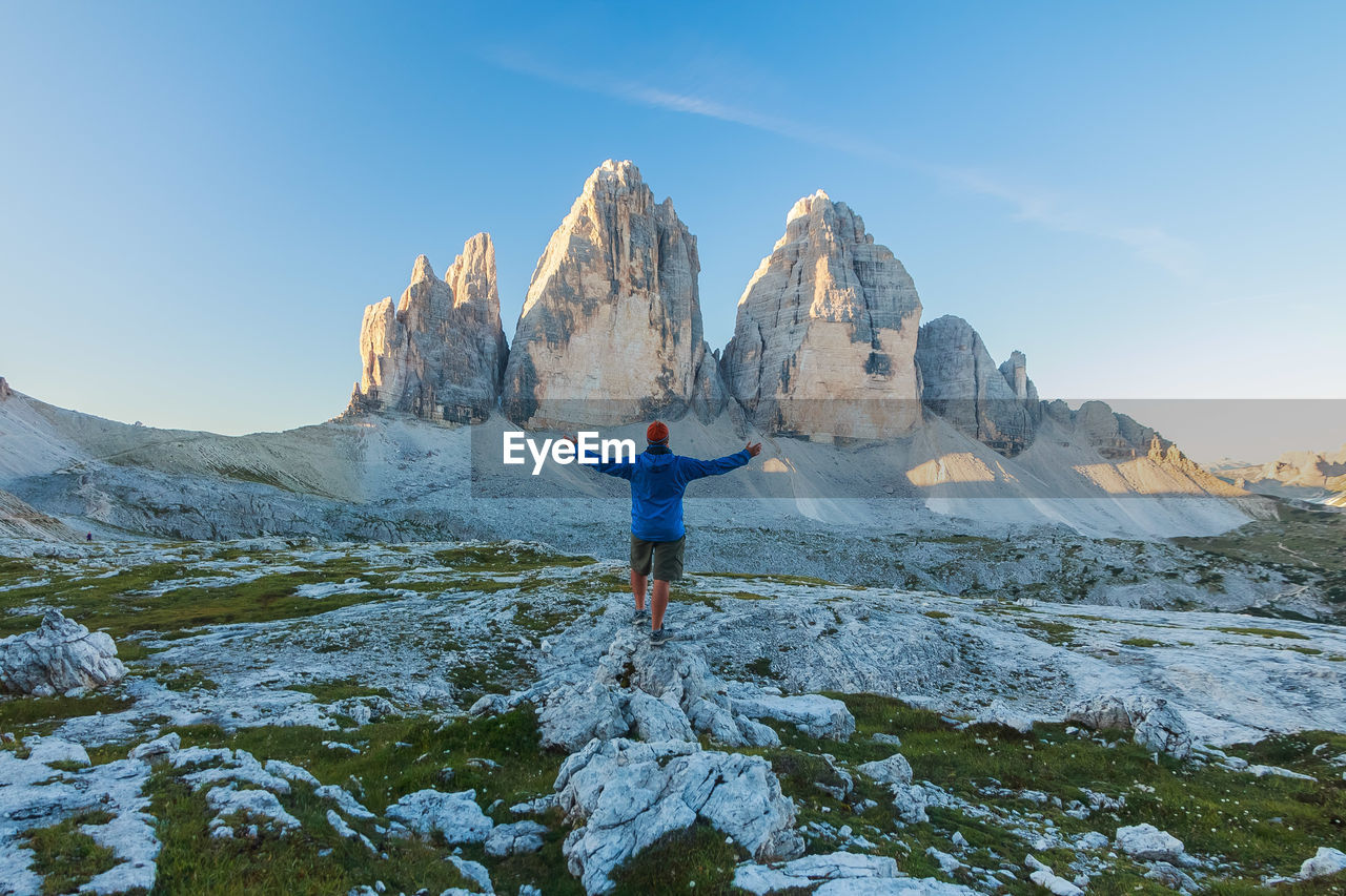 Rear view of person standing on rock against sky