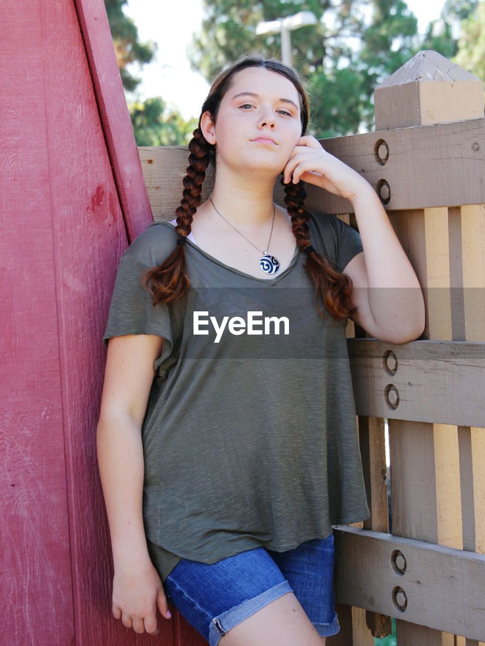 Portrait of teenage girl standing by fence