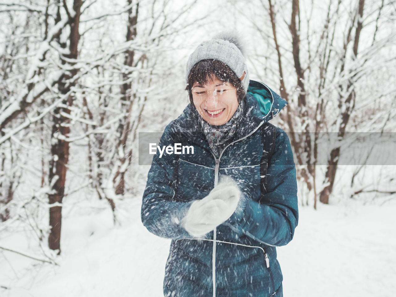 Smiling woman is playing with snow. fun in snowy winter forest. woman laughs and walks through wood.