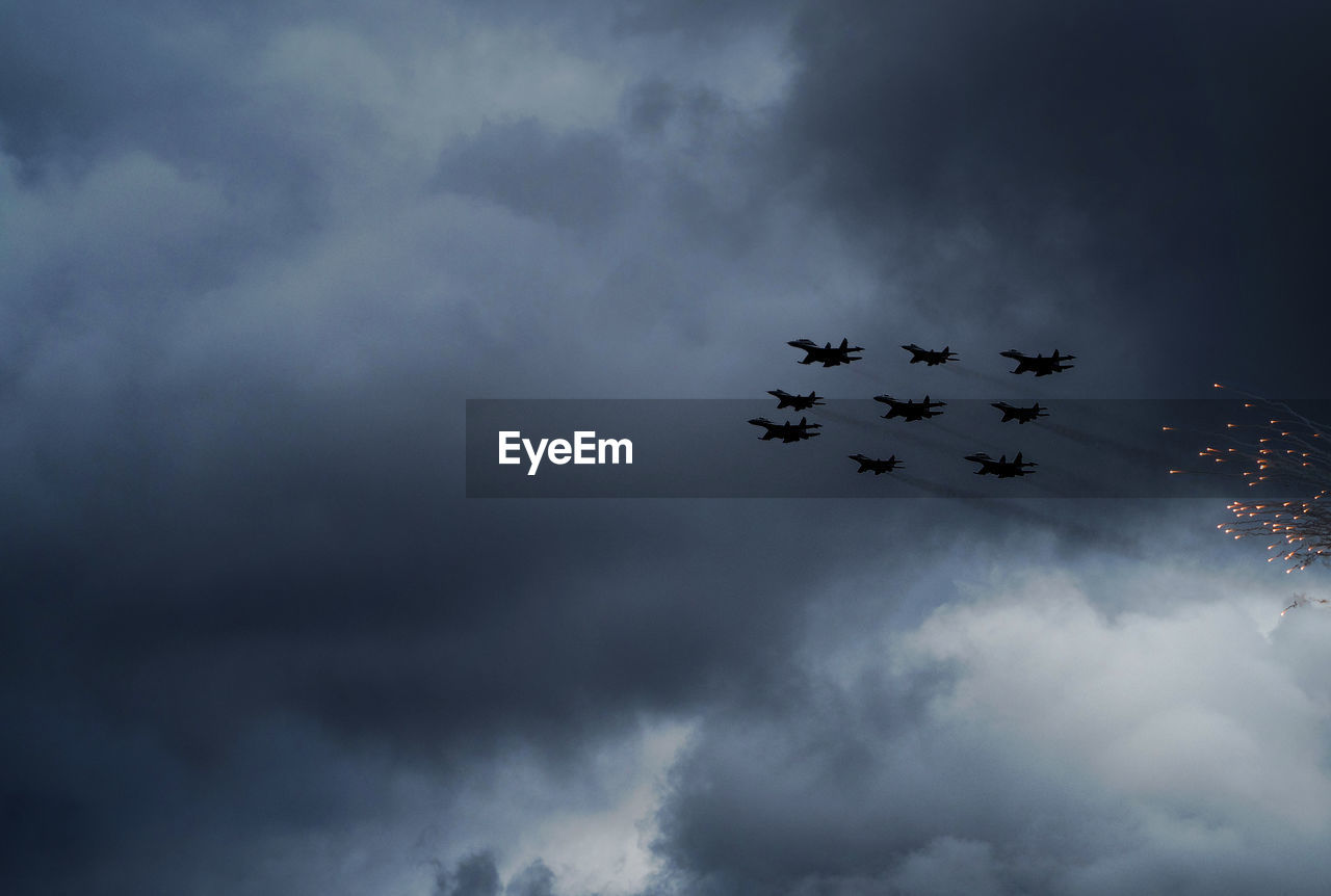 Low angle view of airplanes against clouds