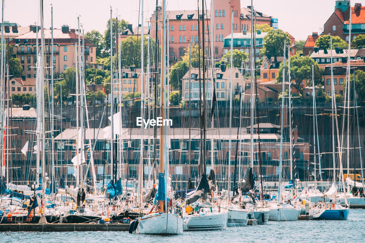 Sailboats moored at harbor in city