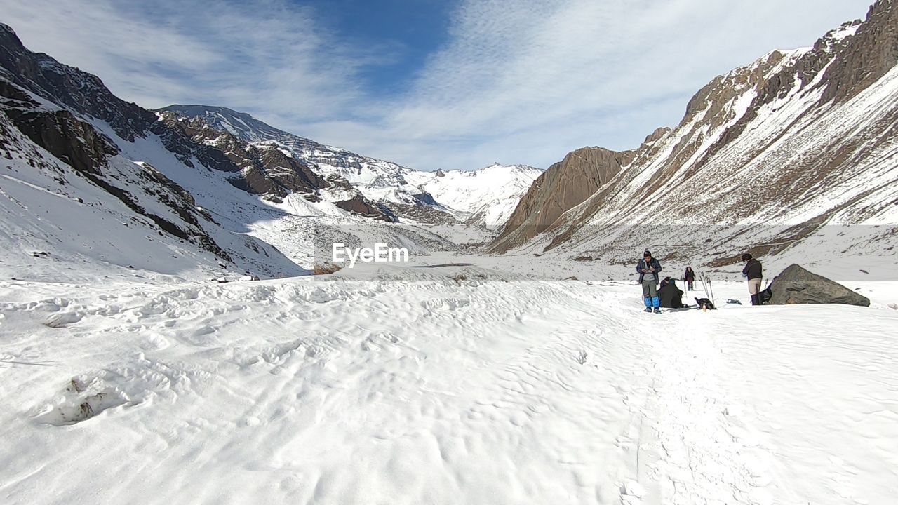 PEOPLE WALKING ON SNOWCAPPED MOUNTAIN AGAINST SKY