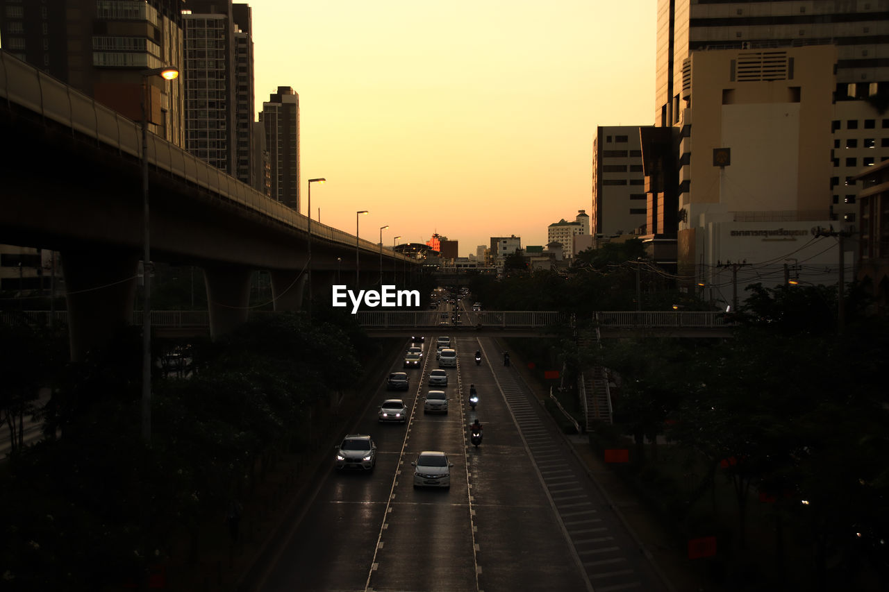 Cars on road in city against sky during sunset