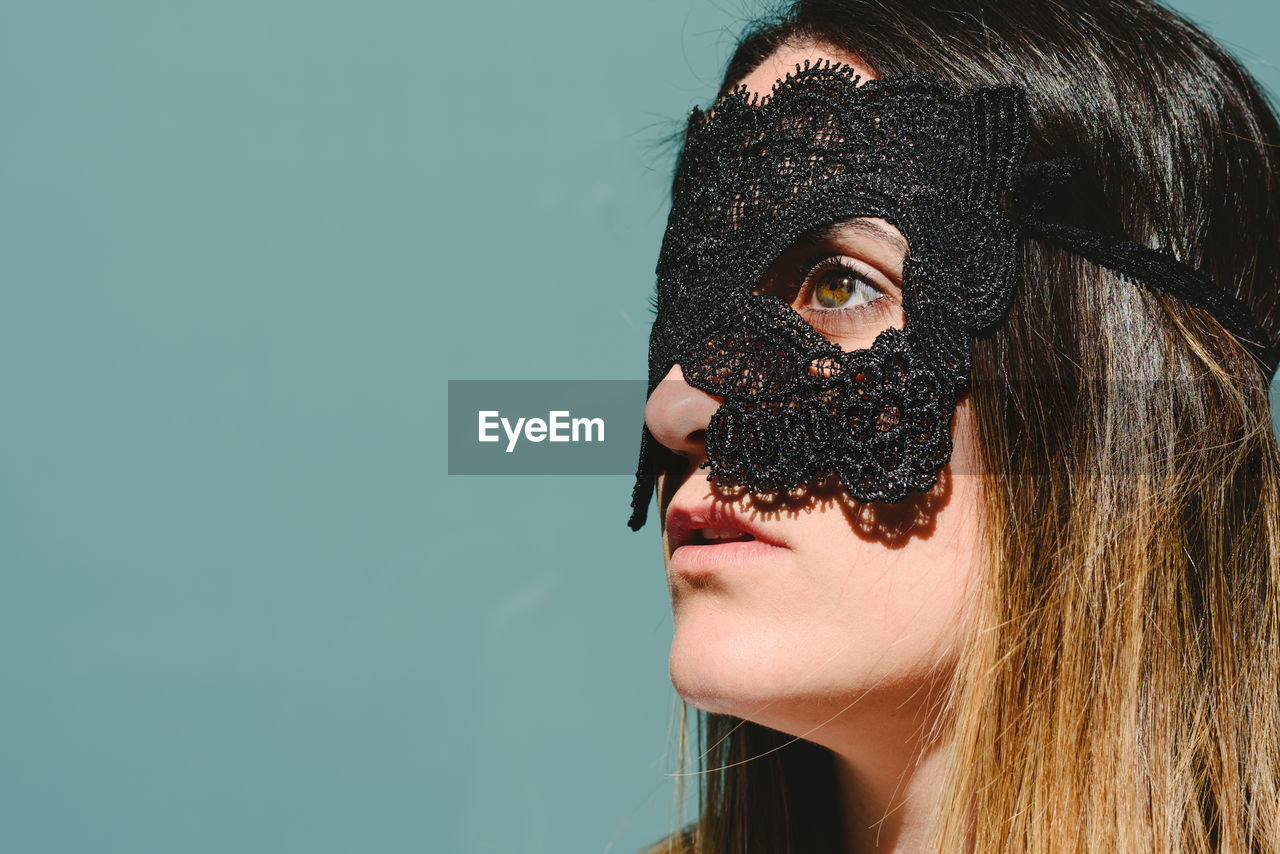 Woman wearing eye mask against blue background