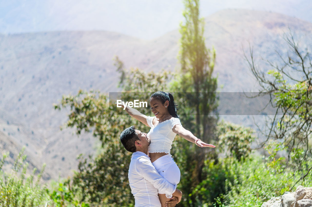 Man carrying woman against mountain