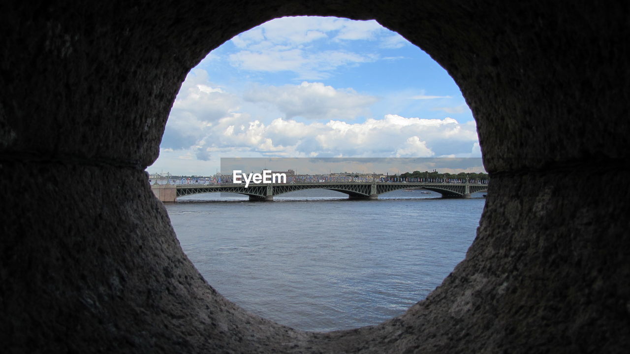 Scenic view of bridge over sea seen through hole against sky