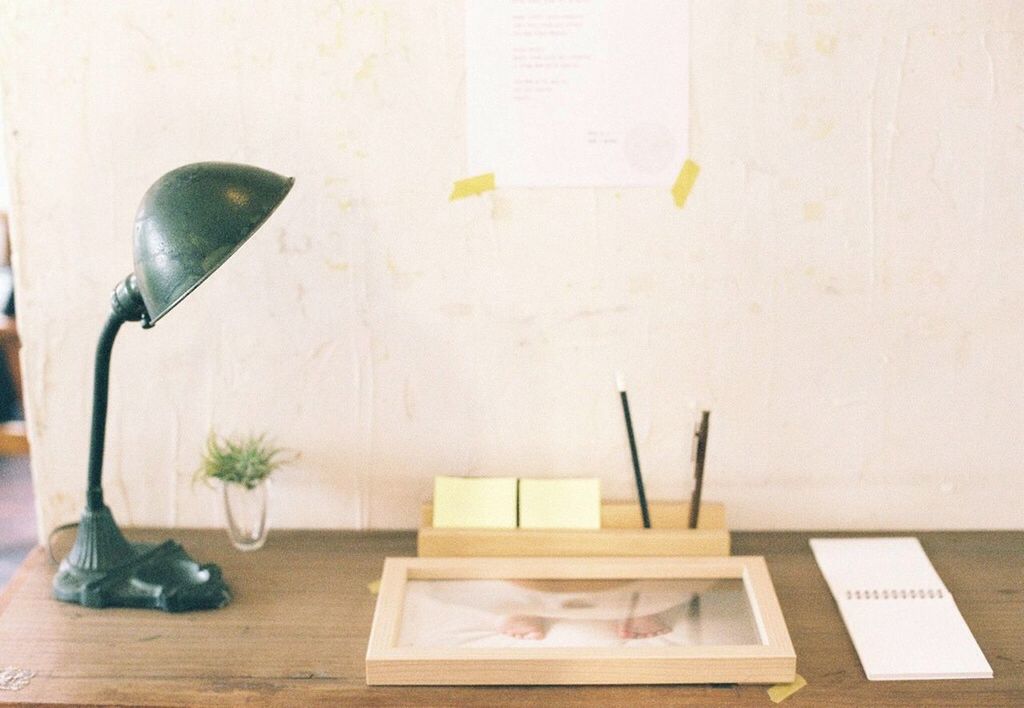 Desk lamp on wooden table by wall at home