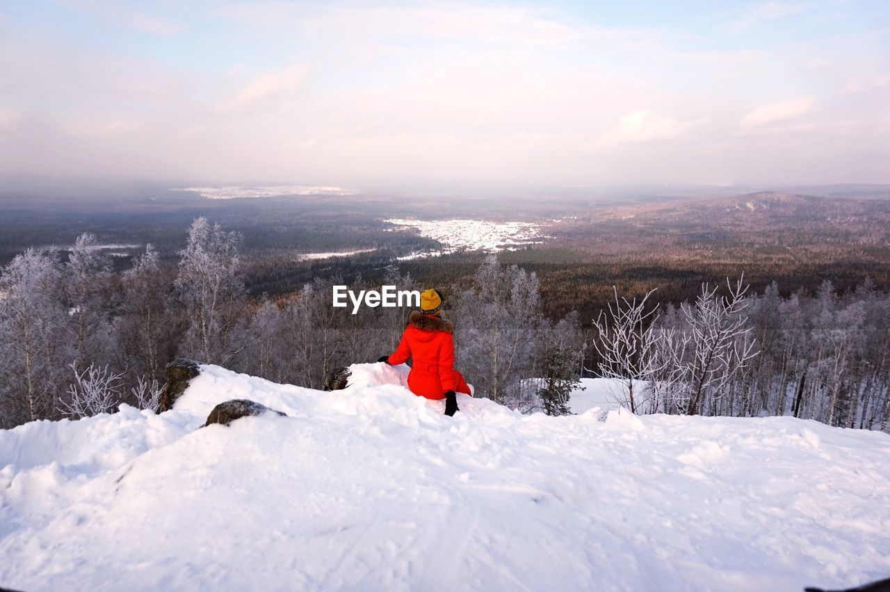 Rear view of woman on snow covered landscape against sky