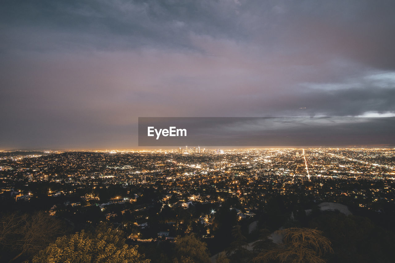 HIGH ANGLE VIEW OF ILLUMINATED BUILDINGS AT SUNSET