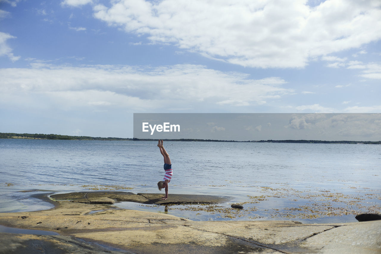 Girl doing handstand at water