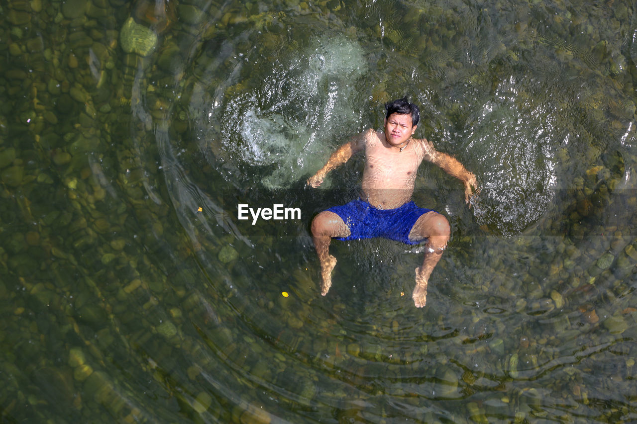 High angle view of shirtless man swimming in river
