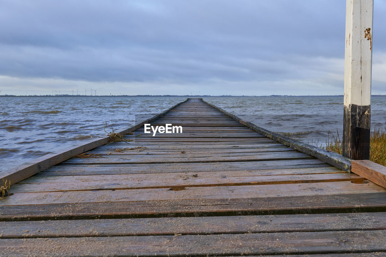 Wooden pier over sea against sky