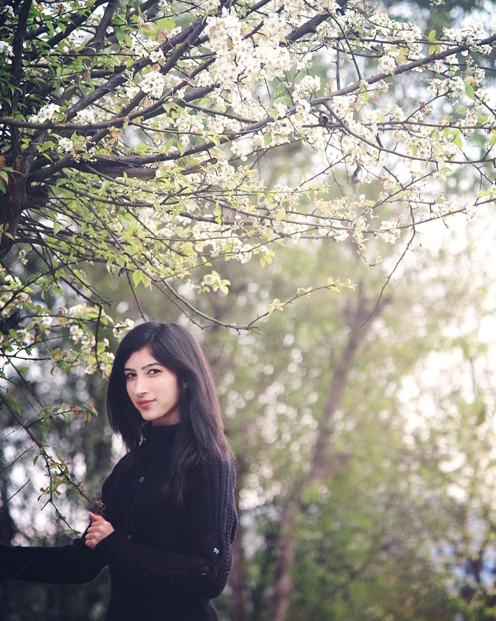 Portrait of beautiful woman standing by tree