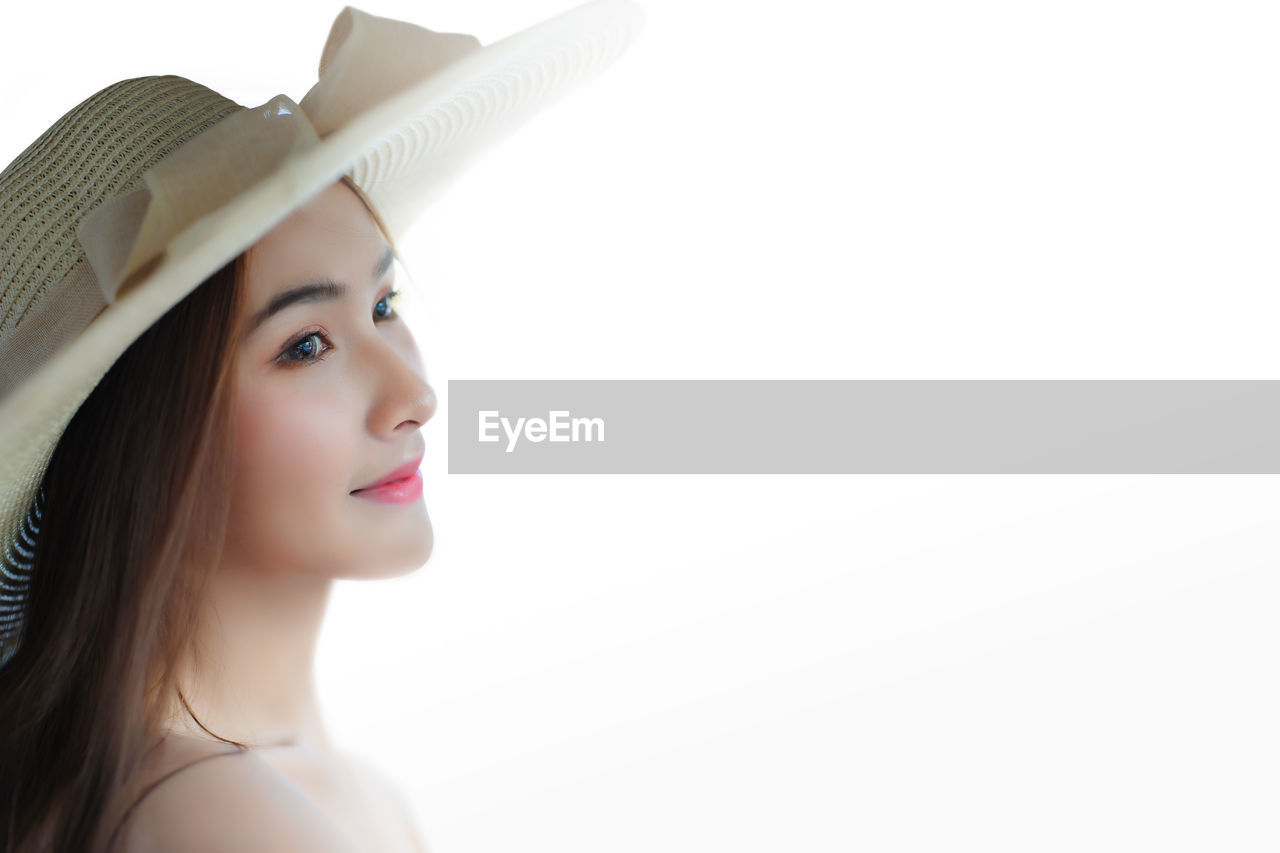 PORTRAIT OF BEAUTIFUL YOUNG WOMAN WITH HAT AGAINST WHITE BACKGROUND