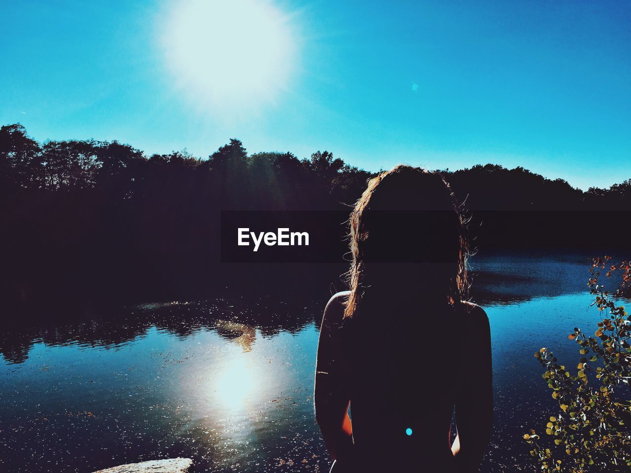 Woman standing in front of lake during sunny day