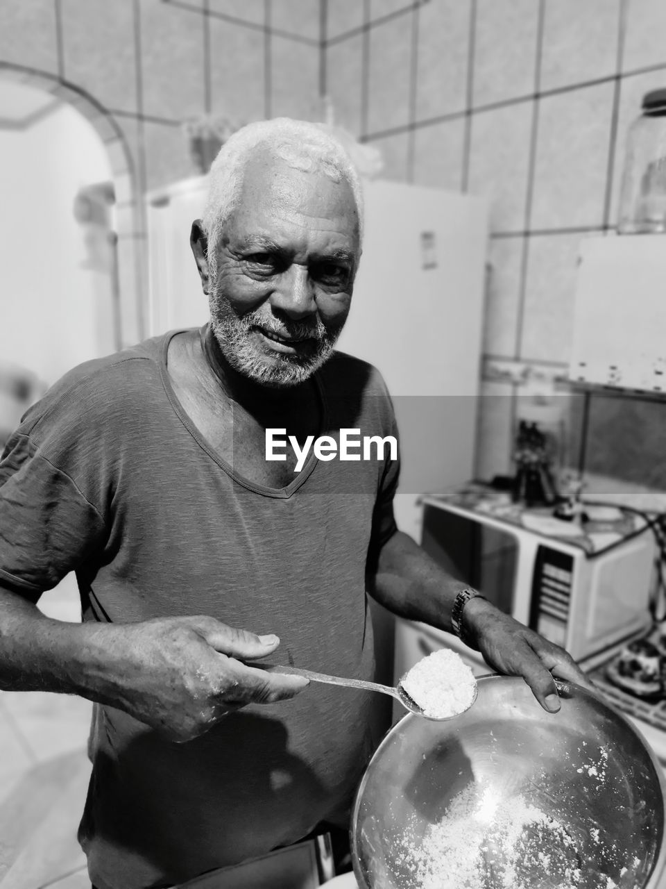 MAN HOLDING CAMERA IN KITCHEN AT HOME