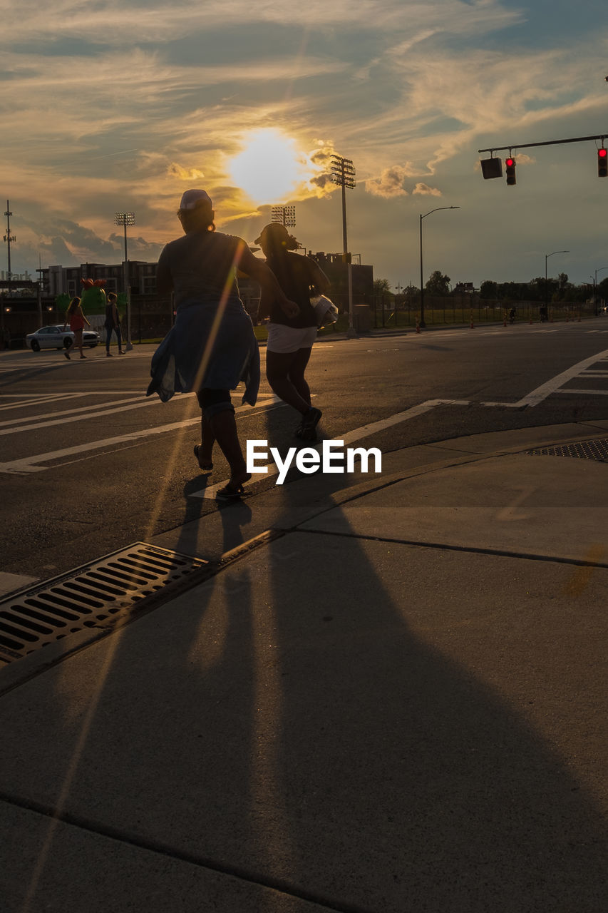 REAR VIEW OF PEOPLE WALKING ON ROAD IN CITY