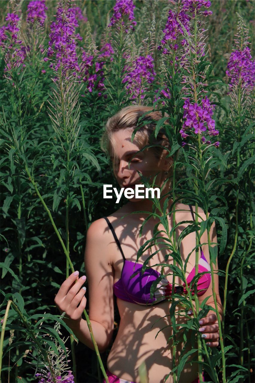 Woman in bikini standing amidst plants