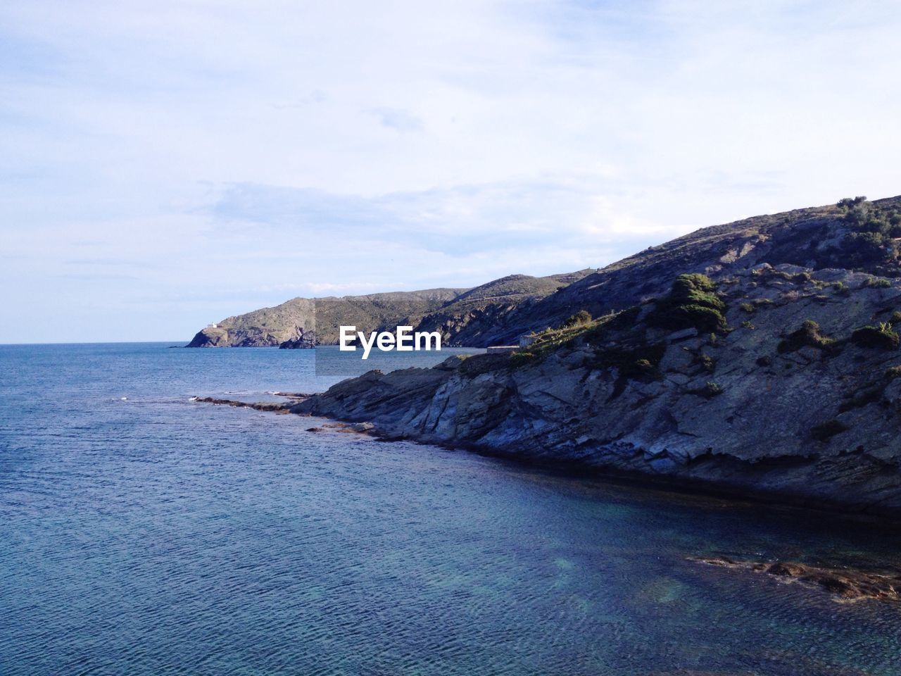 Scenic view of sea by mountains against sky