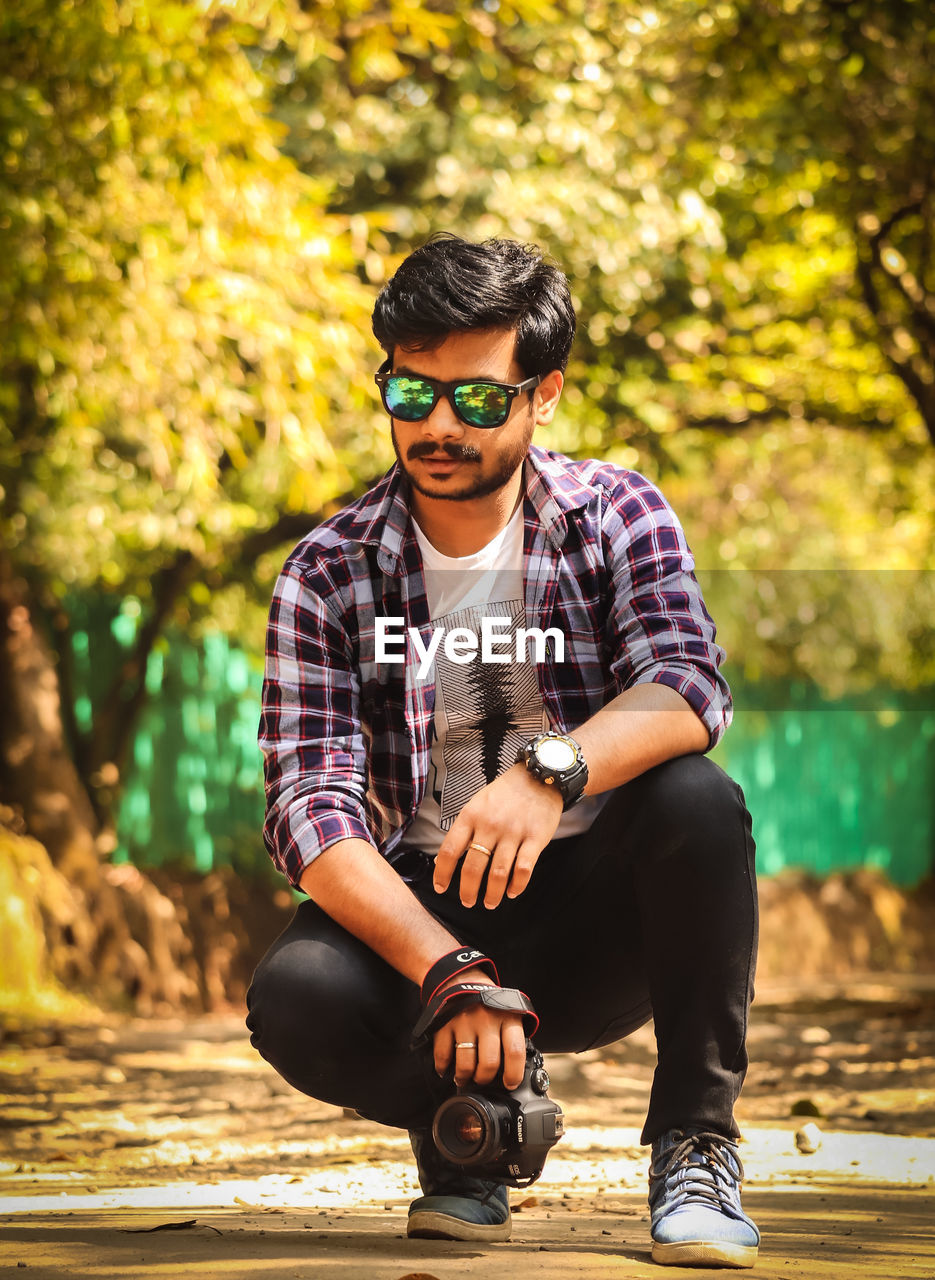 Portrait of young man wearing sunglasses sitting outdoors