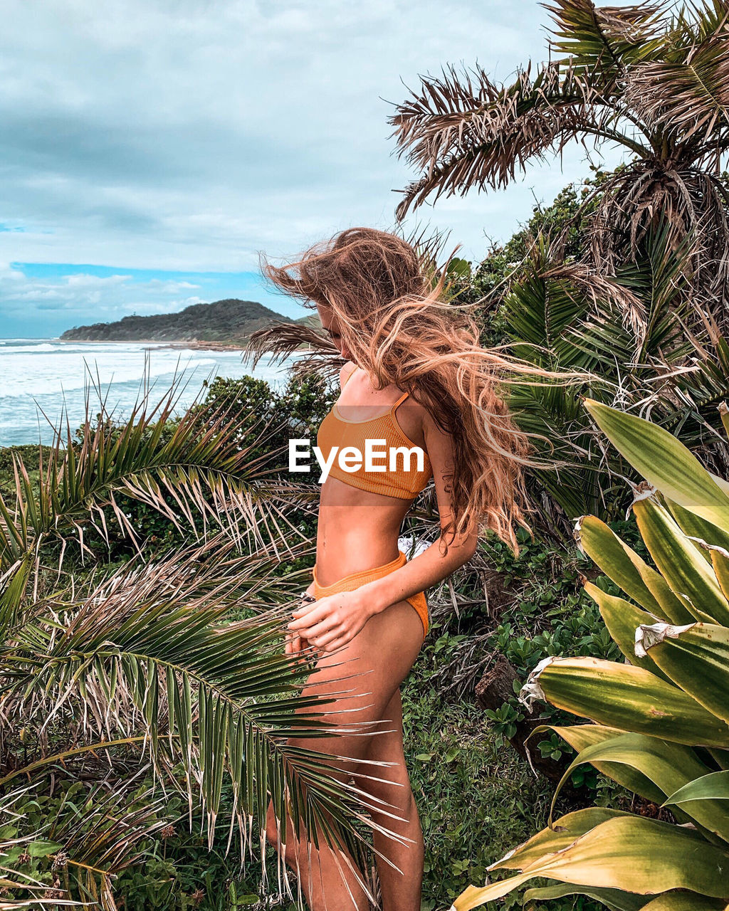 Side view of girl wearing bikini amidst plants