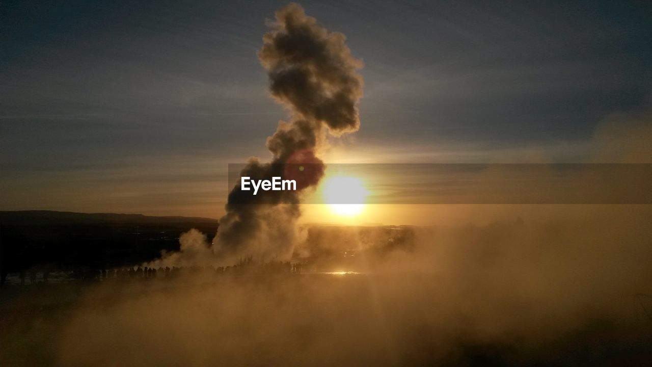 Scenic view of strokkur geyser against sky at sunset