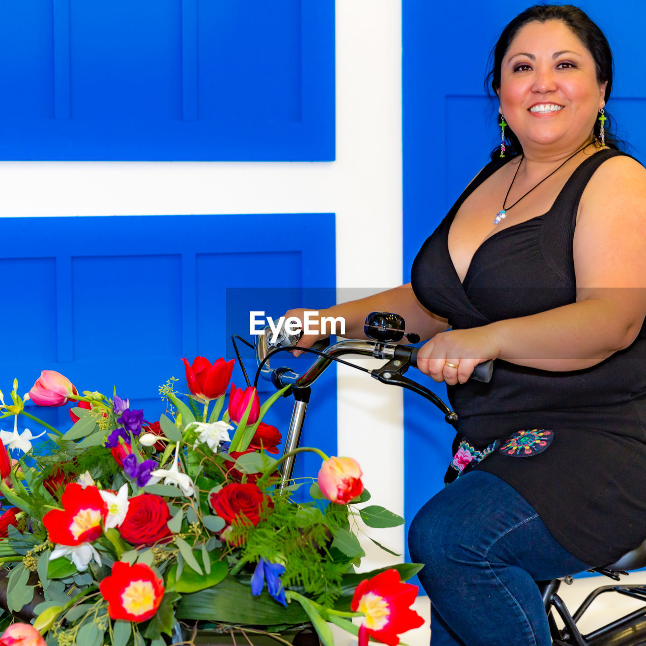 PORTRAIT OF A SMILING WOMAN AGAINST BLUE WALL