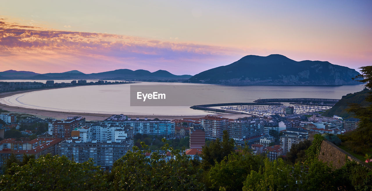 High angle view of buildings by sea against sky during sunset