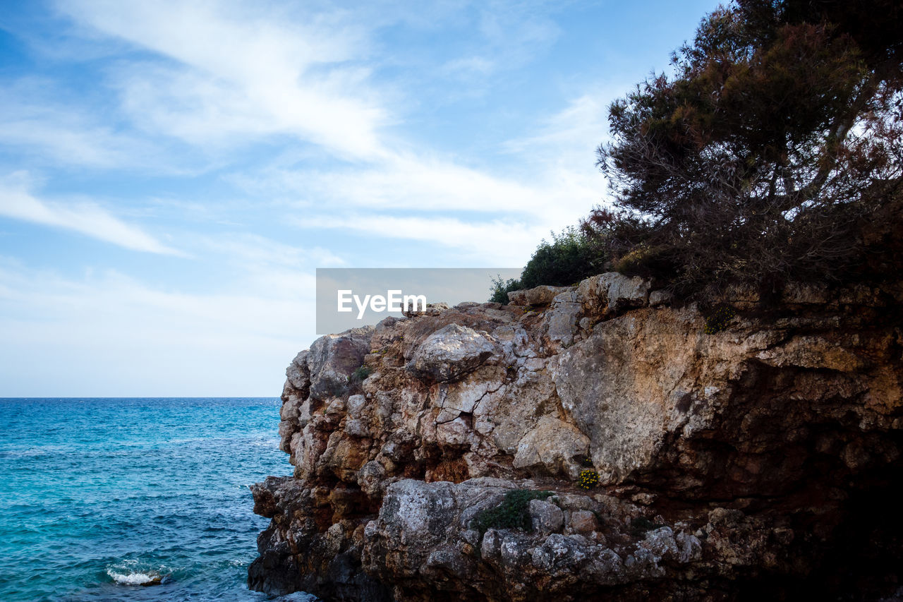 ROCK FORMATION ON SEA AGAINST SKY