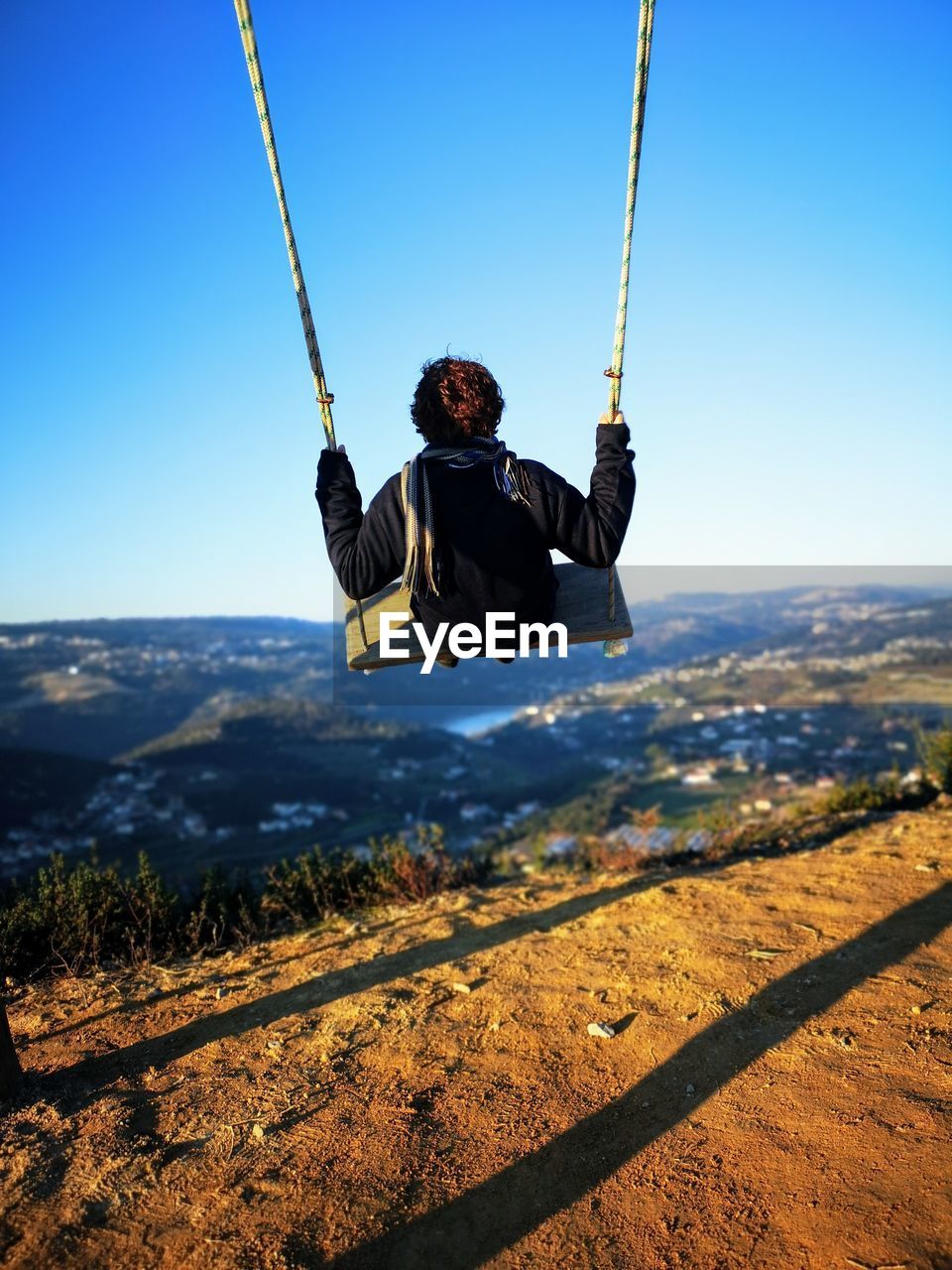 Rear view of woman swinging on field against sky