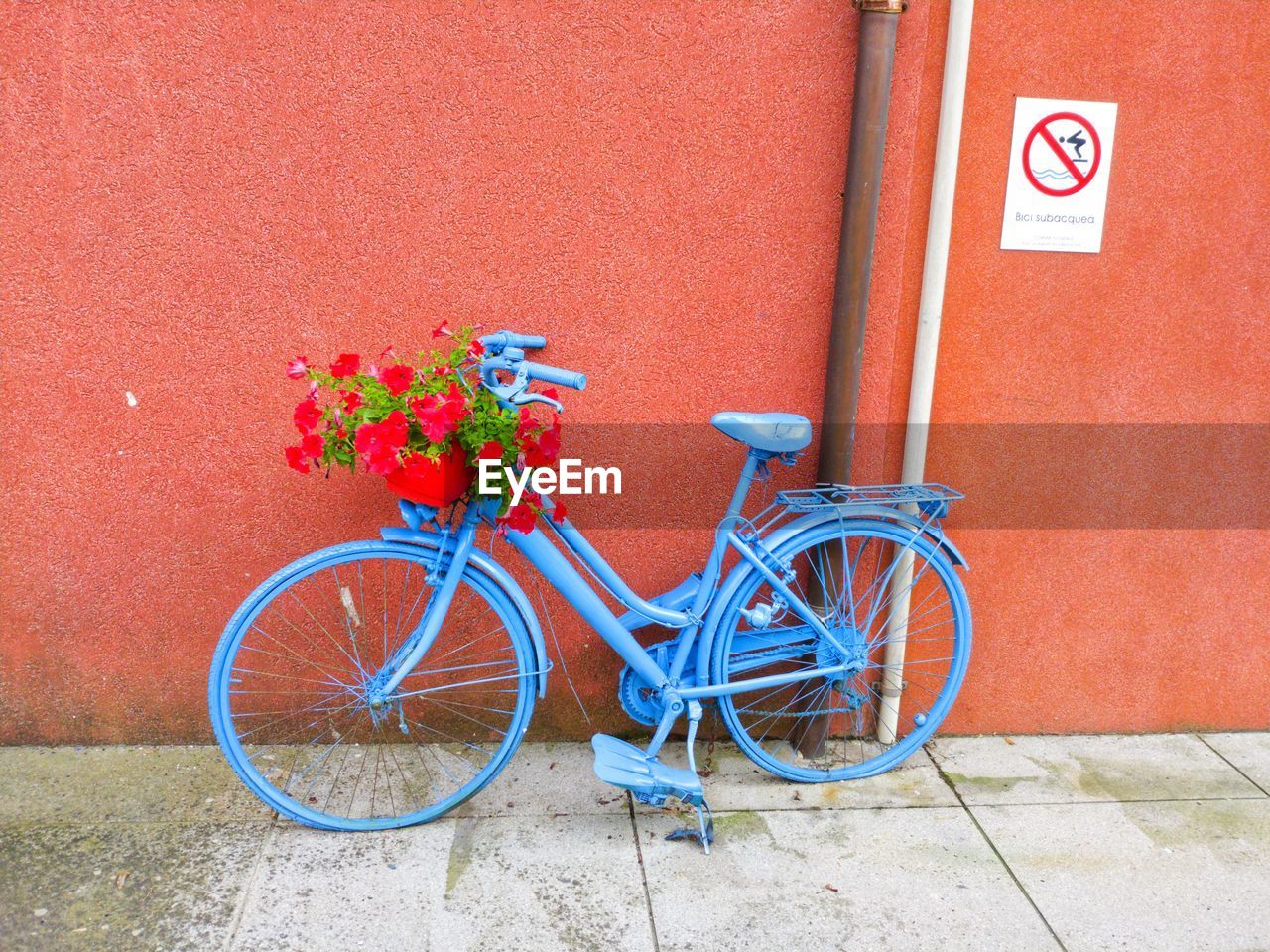 Bicycle parked against red wall