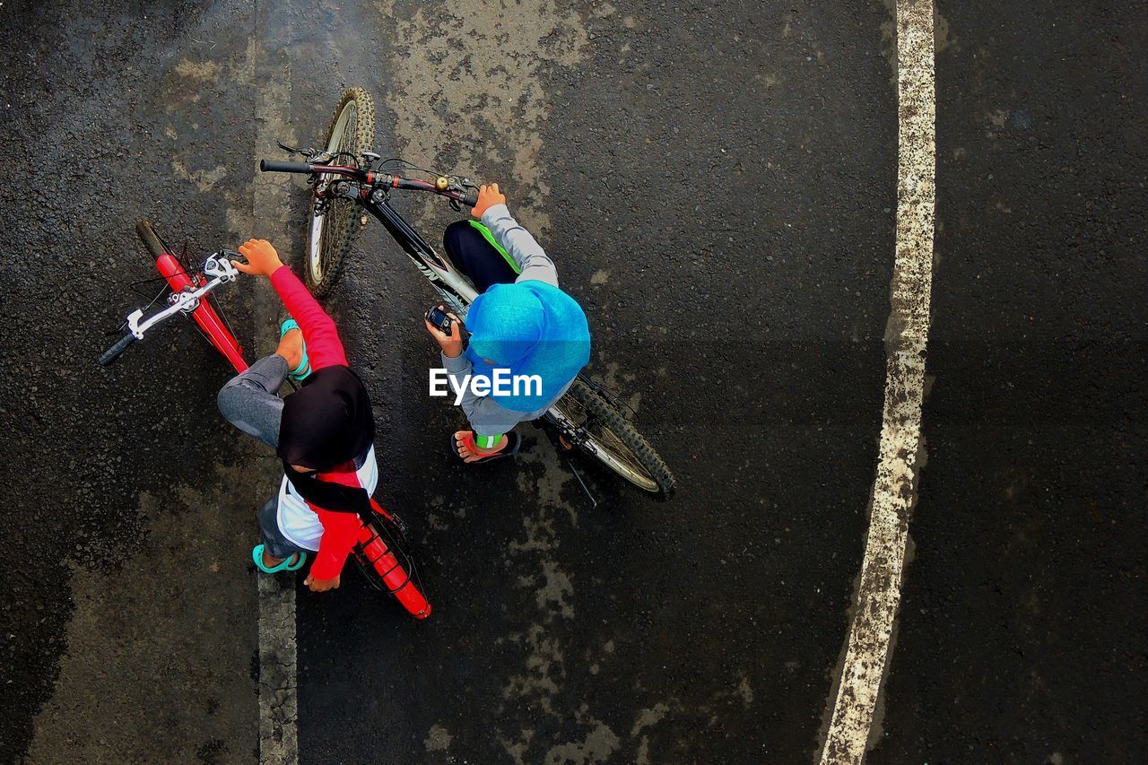 HIGH ANGLE VIEW OF PEOPLE WITH BICYCLE ON ROAD IN CITY