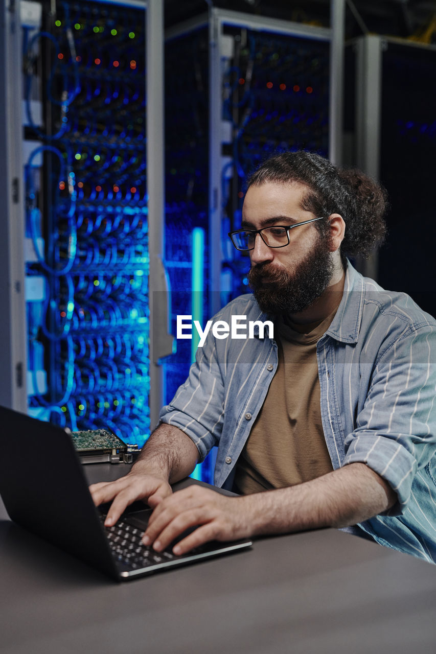 It engineer using laptop at desk in control room