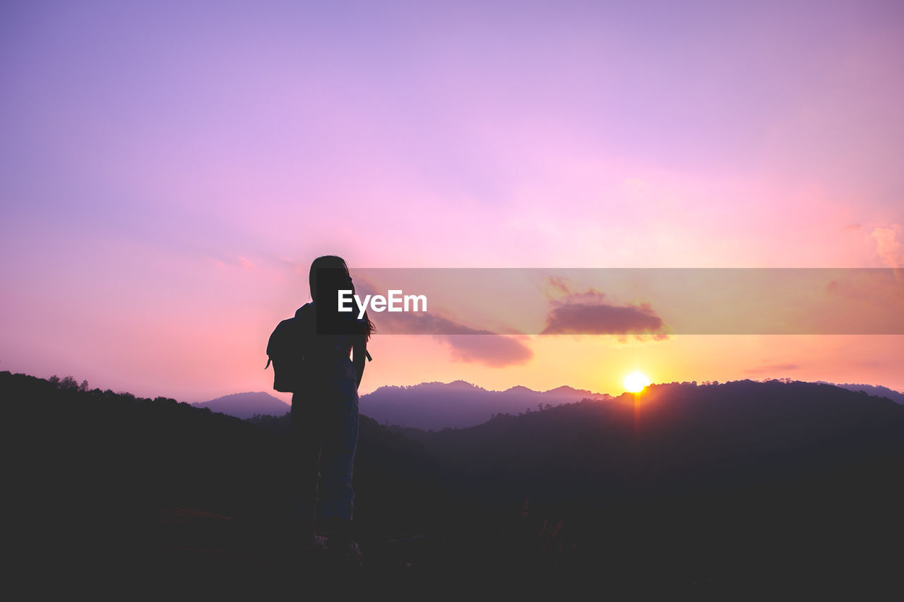 SILHOUETTE MAN STANDING ON PURPLE AGAINST SKY DURING SUNSET