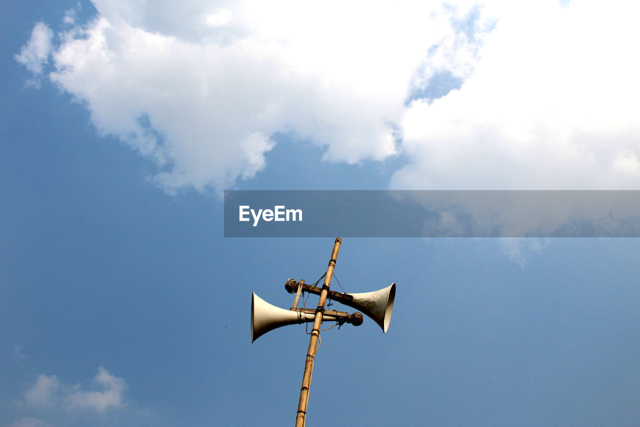 Low angle view of megaphones on bamboo against sky