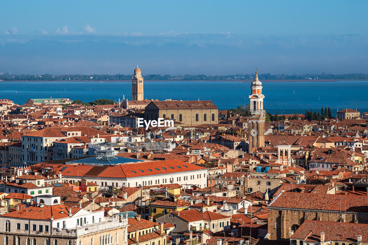 Aerial view of townscape by sea against sky