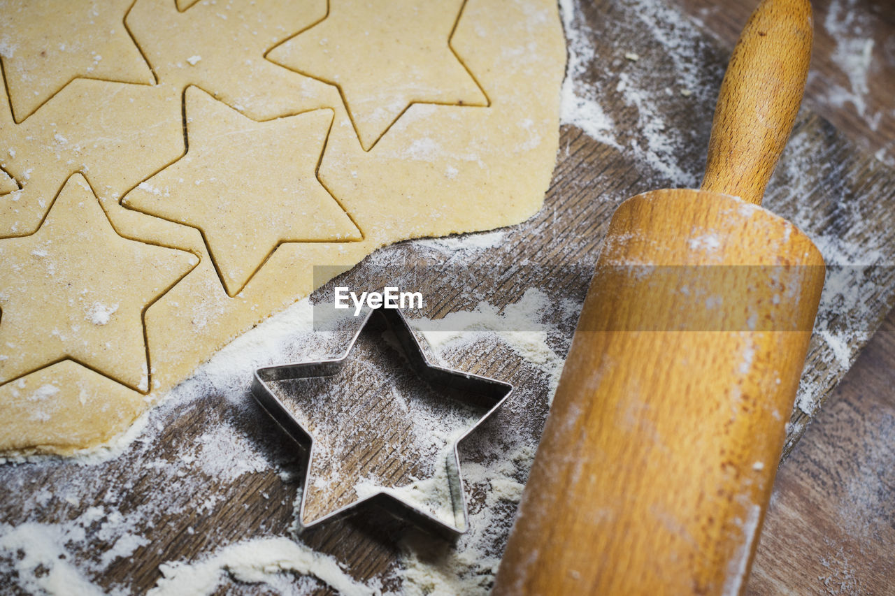High angle view of star shape cookies with rolling pin and cutter on table